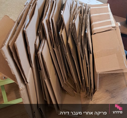 ערימה של קרטונים מקופלים ומפורקים בבית לאחר פריקת תכולה